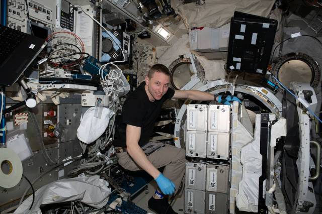 NASA astronaut and Expedition 69 Flight Engineer Woody Hoburg removes the NanoRacks CubeSat Deployer from the Kibo laboratory module's airlock.