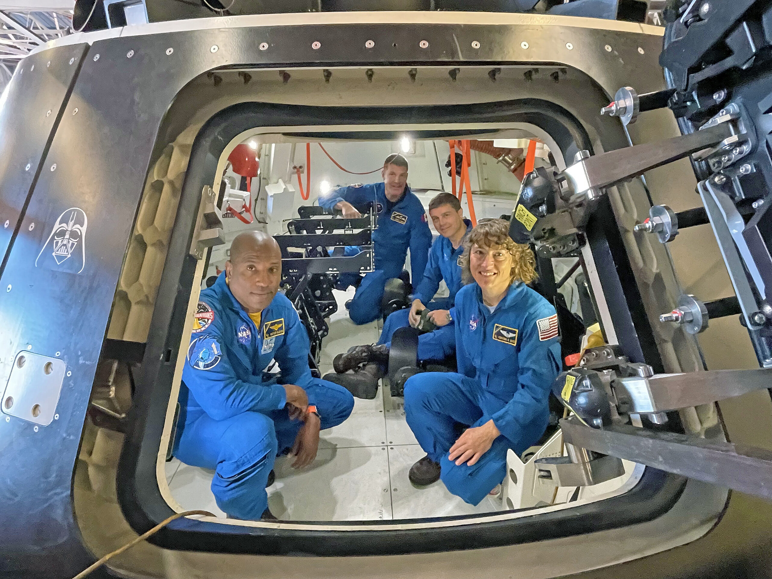Artemis II astronauts sit inside a replica of the Orion spacecraft at Naval Base San Diego.