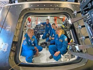 Artemis II astronauts sit inside a replica of the Orion spacecraft at Naval Base San Diego.