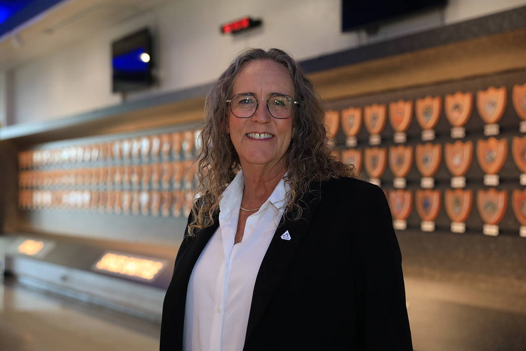 Systems Engineering Supervisor Amy Lendian smiles at the camera in a white collared shirt and a black blazer. She is wearing an Artemis pin on her lapel. The background is out of focus.