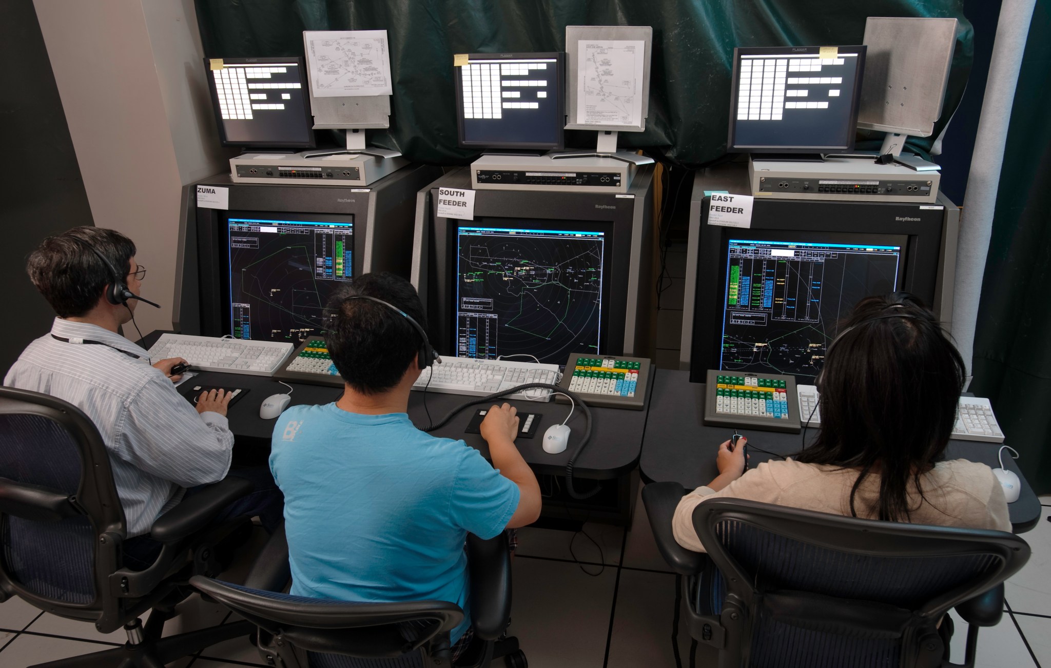 Three people at workstations in ATC simulation lab