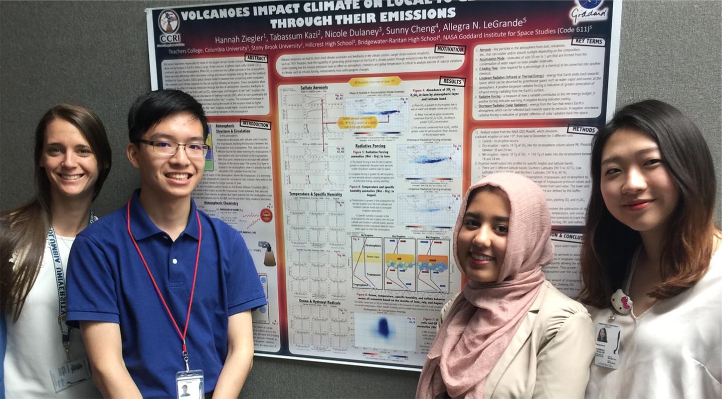 Photo of a teacher and three students standing alongside a poster paper about volcanoes' impact on climate.