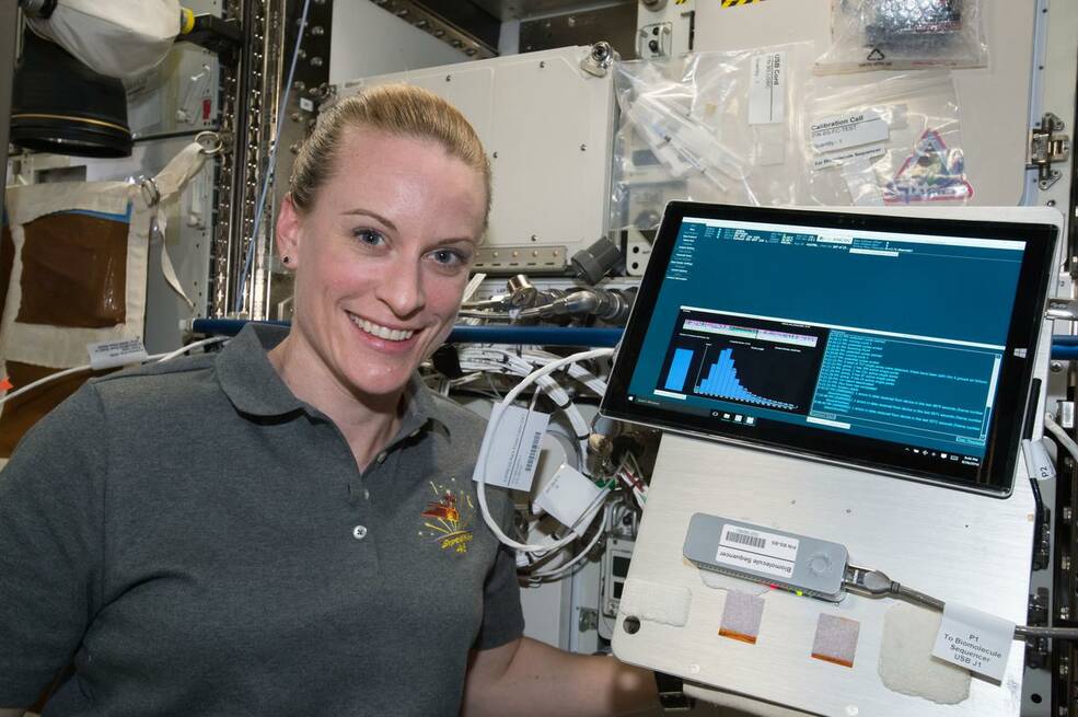 NASA astronaut Kate Rubins poses for a photo with Biomolecule Sequencer experiment hardware (Surface Pro 3 tablet and MinION) during the first sample initialization run.