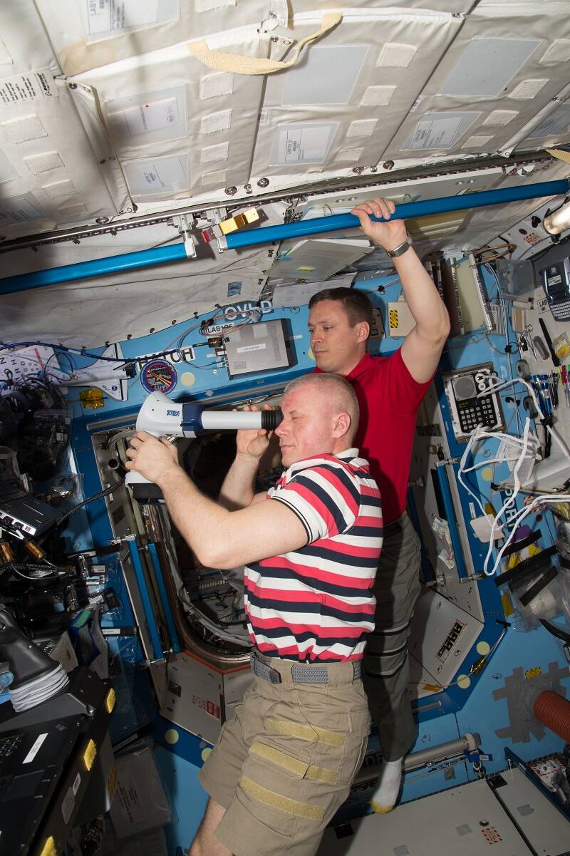 Roscosmos cosmonaut Oleg Novitskiy conducts an eye examination for the Fluid Shifts experiment with assistance from NASA astronaut Jack Fischer.