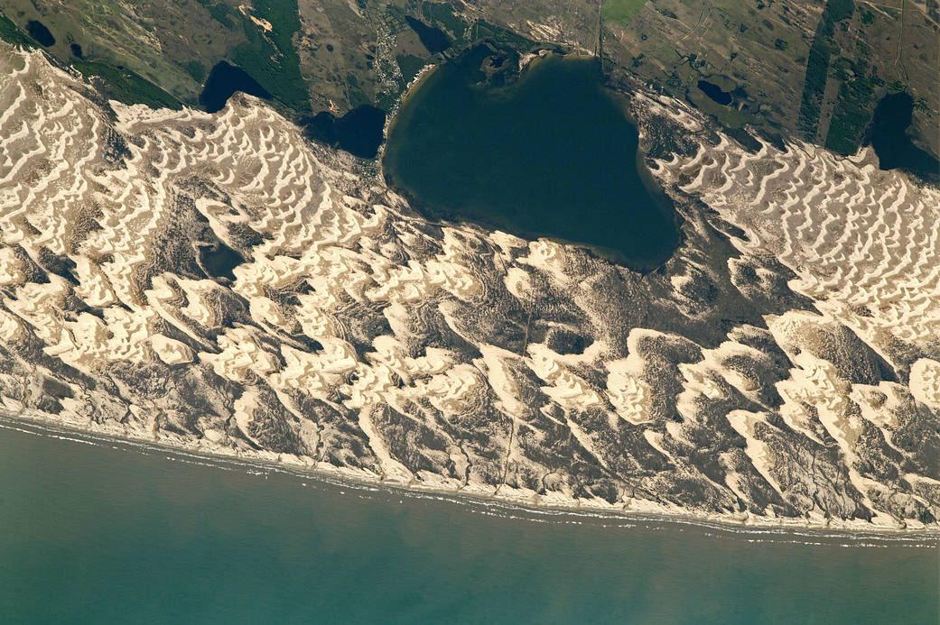 An astronaut aboard the International Space Station captured this photograph of Lagoa dos Barros and crescent-shaped barchan dunes on the Atlantic coastline of southern Brazil.