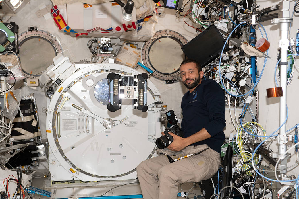 Astronaut Sultan Alneyadi observes a free-flying Astrobee robotic assistant