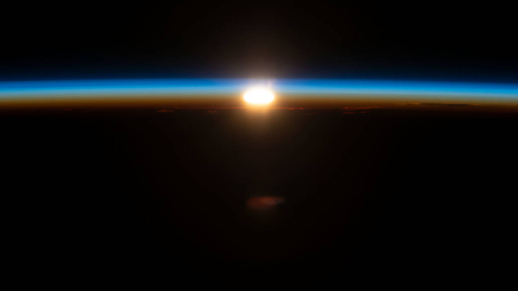 An orbital sunrise illuminates Earth's atmosphere