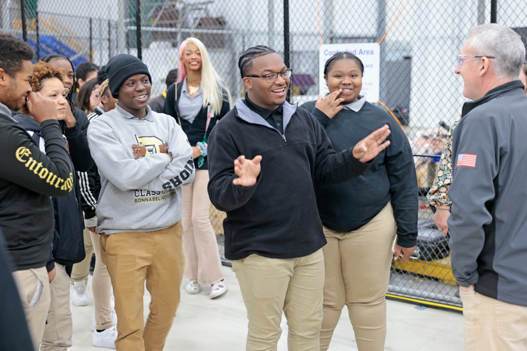 Four students smile as they speak with a worker at Michoud Assembly Facility.