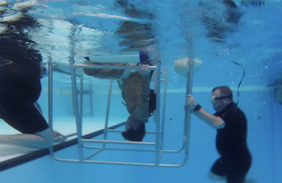 NASA pilot Scott Howe, center, exits the helicopter egress frame during dunker training while Federal Aviation Administration training specialist James Sheerin, right, holds the frame on April 12, 2023, at the FAA Civil Aerospace Medical Institute.