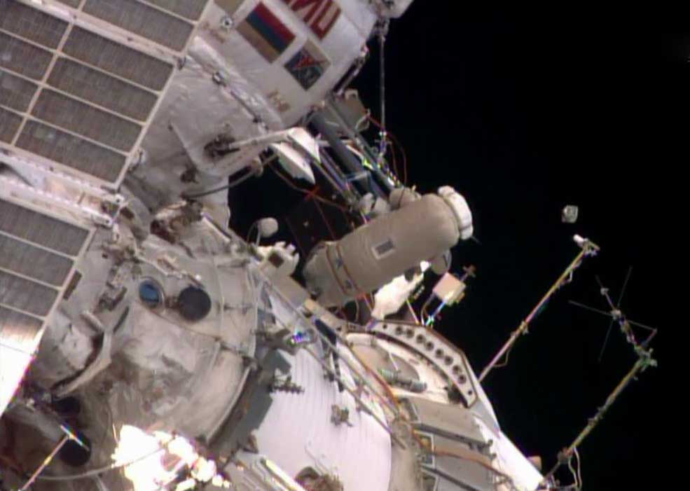 Flight Engineer Oleg Artemyev deploys the Chasqui 1 nanosatellite outside the Pirs docking compartment near the beginning of Monday's spacewalk.