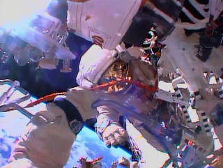The view from cosmonaut Oleg Kotov's helmet camera shows fellow spacewalker Sergey Ryazanskiy as the two work with an EVA workstation and biaxial pointing platform.