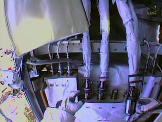 Spacewalker Rick Mastracchio works to disconnect the fluid lines from the degraded pump module in this view from the NASA astronaut's helmet camera.