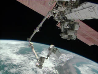 Astronaut Mike Hopkins rides the Canadarm2 carrying the 780-pound ammonia pump module as the International Space Station flies over South America.