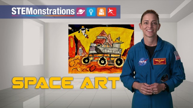 An astronaut wearing a blue flight suit in front of space art hanging on the wall