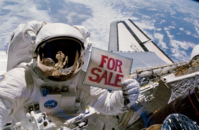 Astronaut Dale A. Gardner, having just completed the major portion of his second extravehicular activity (EVA) period in three days aboard the Earth-orbiting Discovery, holds up a for sale sign.