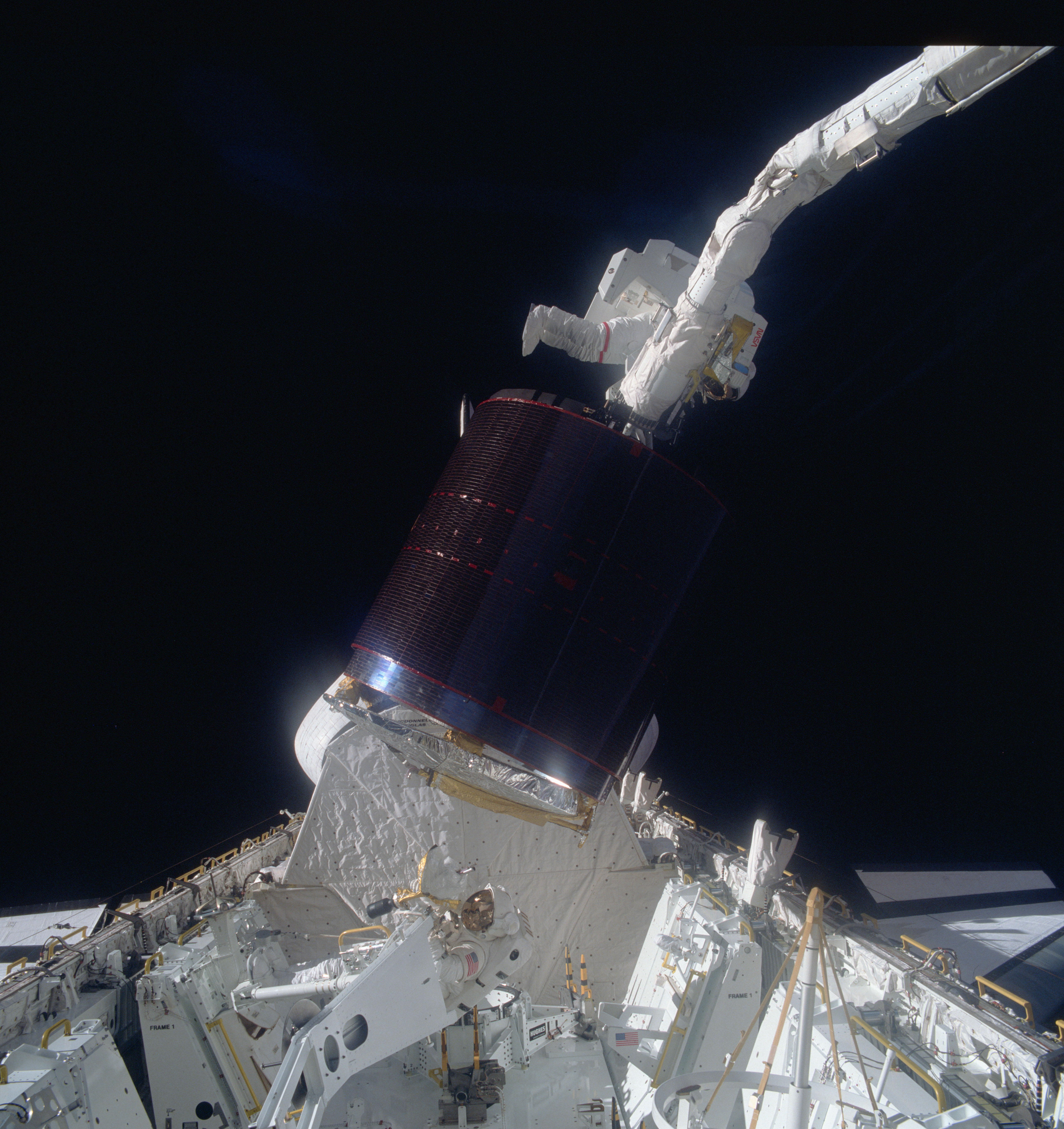 Astronaut Joseph P. Allen IV, top, hangs onto a stinger device as Astronaut Dale A. Gardner in the cargo bay of Discovery waits to assist in the be...