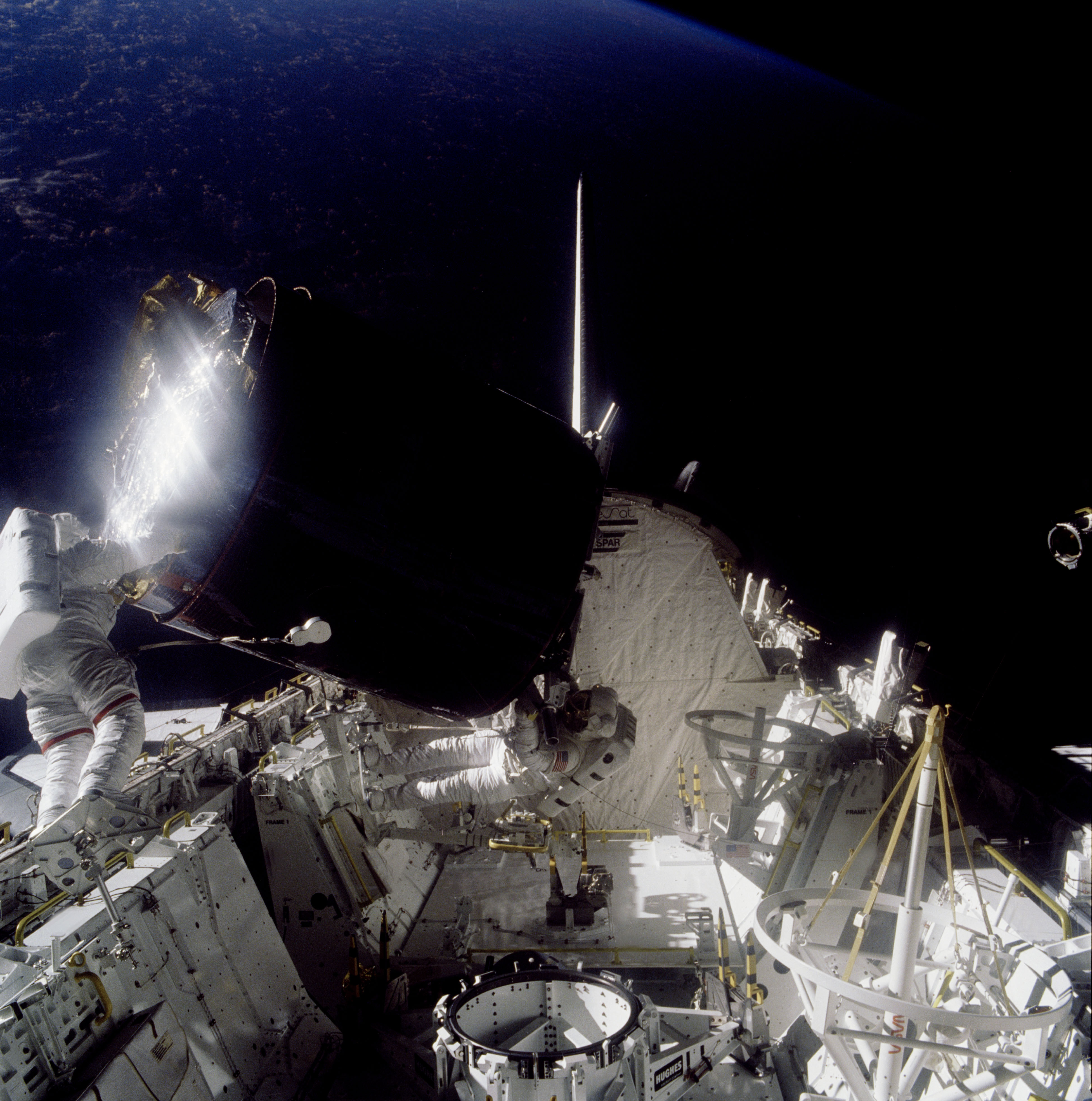 Joe Allen and Dale Gardner during EVA with two satellites in the open shuttle cargo bay.