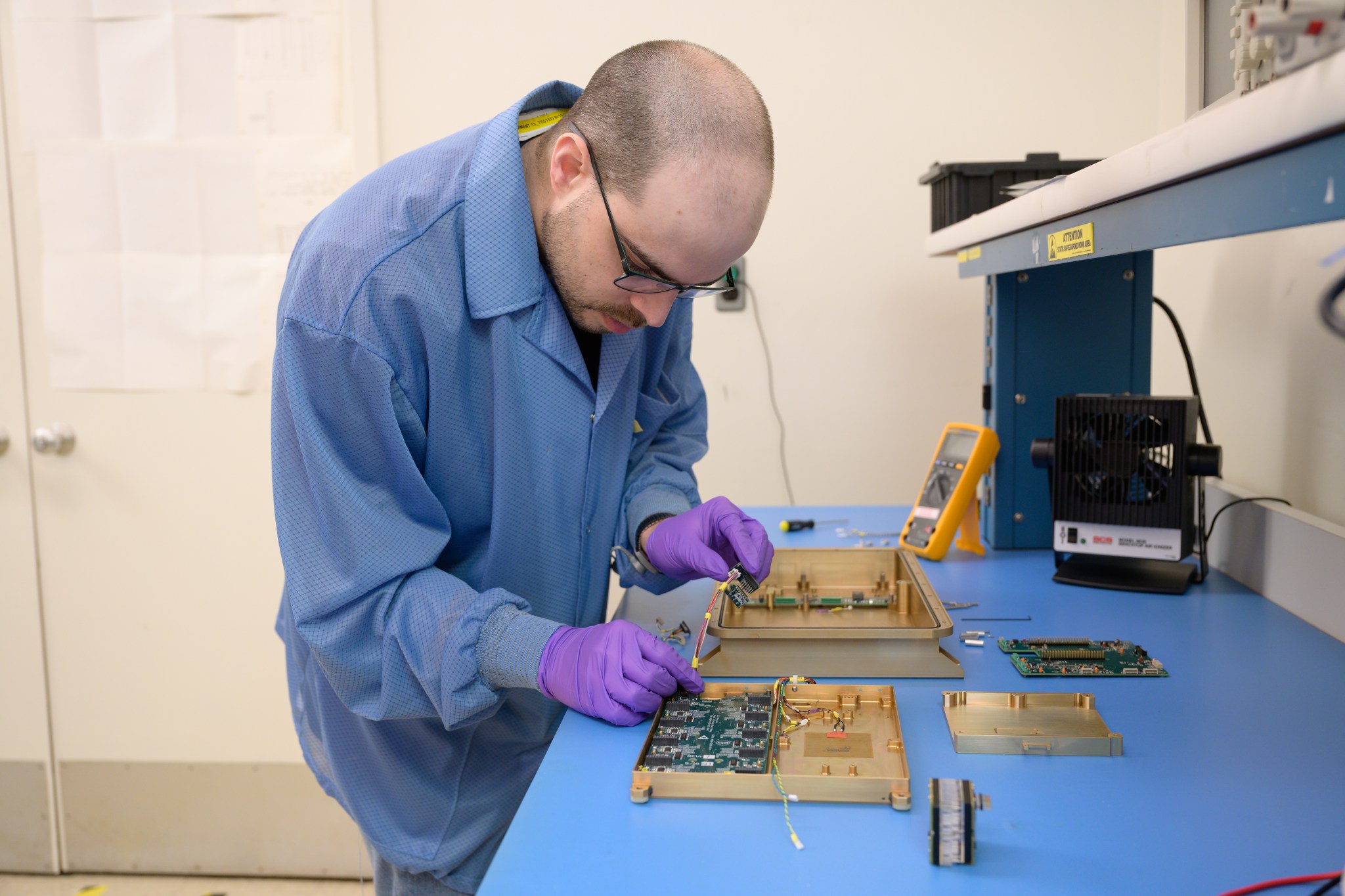 A person inserts a small electrical component into a metal container.