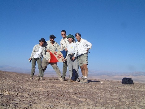 Five people hiking and holding Explorer’s Club flag (red, blue, tan) at Atacama Desert (photo credit G. Kovacs)