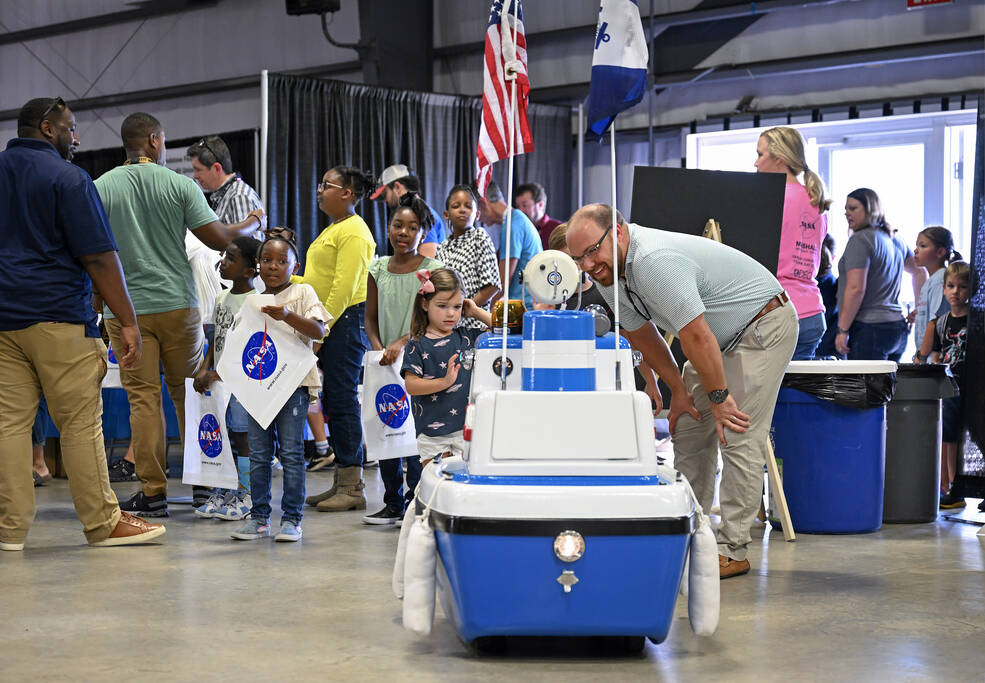 A representative from the Coast Guard Auxiliary, right, introduces Coastie the Safety Boat to a girl at the Take Our Children to Work Day.