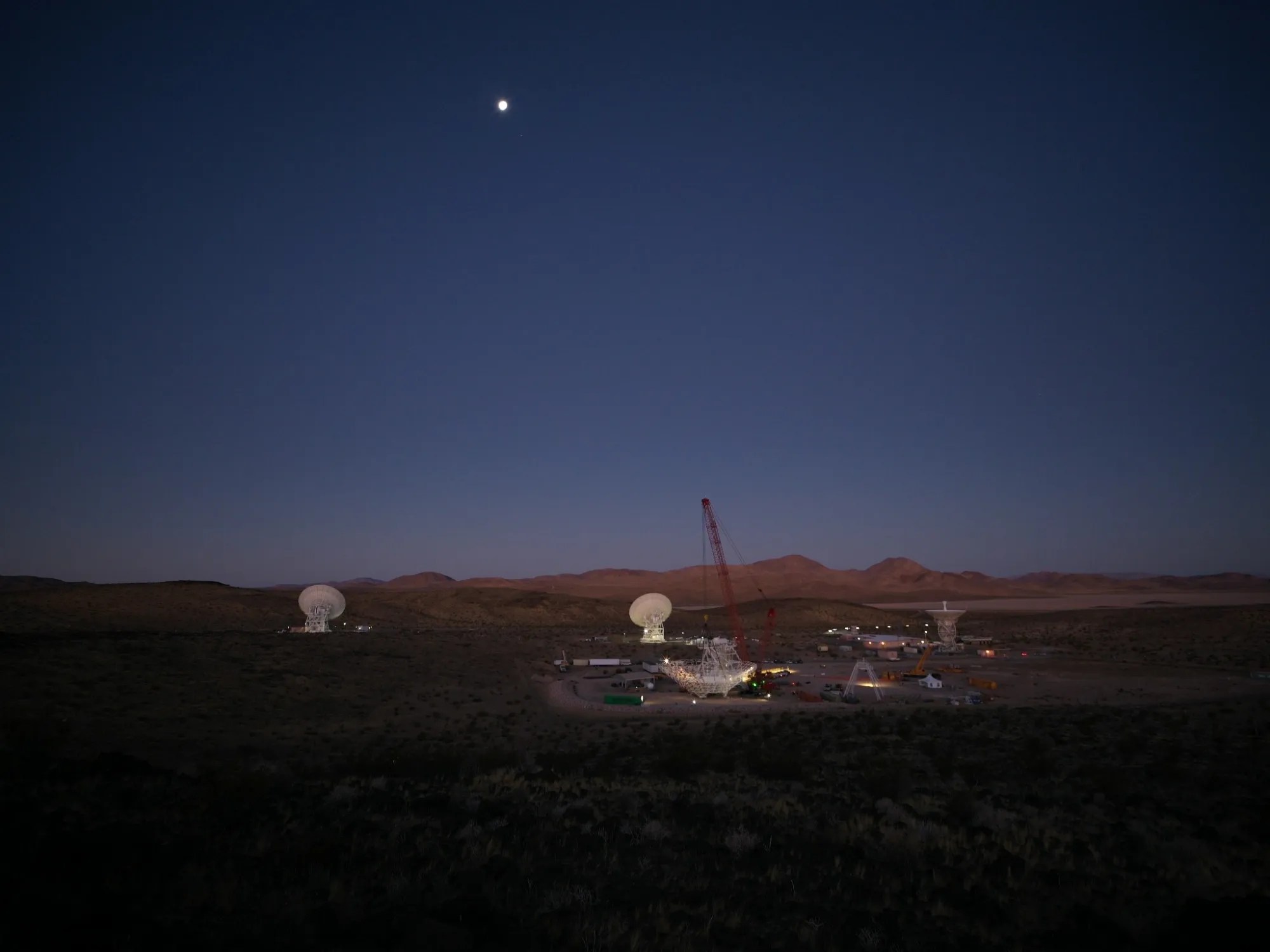 In the early morning of Dec. 18, 2024, a crane looms over the 112-foot-wide (34-meter-wide) steel framework for Deep Space Station 23 reflector dish, which will soon be lowered into position on the antenna’s base structure.