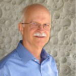 Portrait of Des Morais wearing a blue collar button up dress shirt.