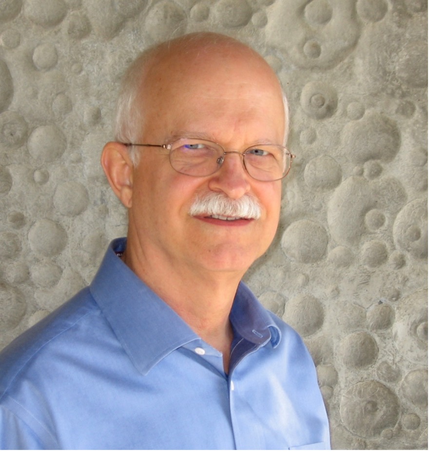 Portrait of Des Morais wearing a blue collar button up dress shirt.