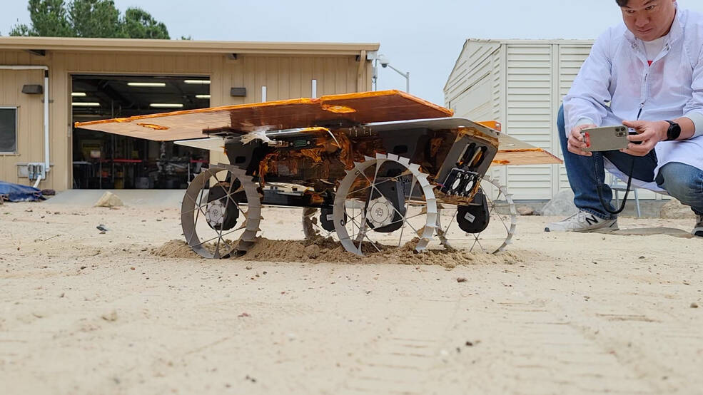 Engineer Kristopher Sherrill observes a development model rover during a test for NASAs CADRE technology demonstration in JPLs Mars Yard in June.