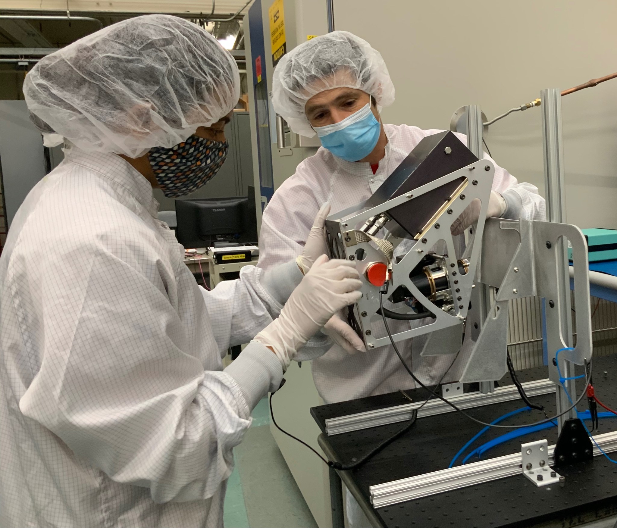 Photo of NASA Ames scientists Eldar Noe Dobrea and Vandana Jha wearing protective equipment while in the FIG laboratory with the NIRVSS instrument.