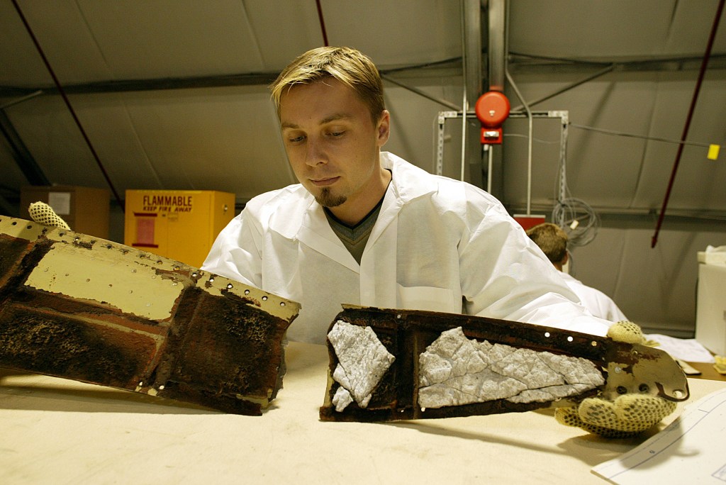 A Columbia Reconstruction Team member works with pieces of debris