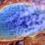 Image of a pruple blue spring surrounded by orange yellow and light purple land