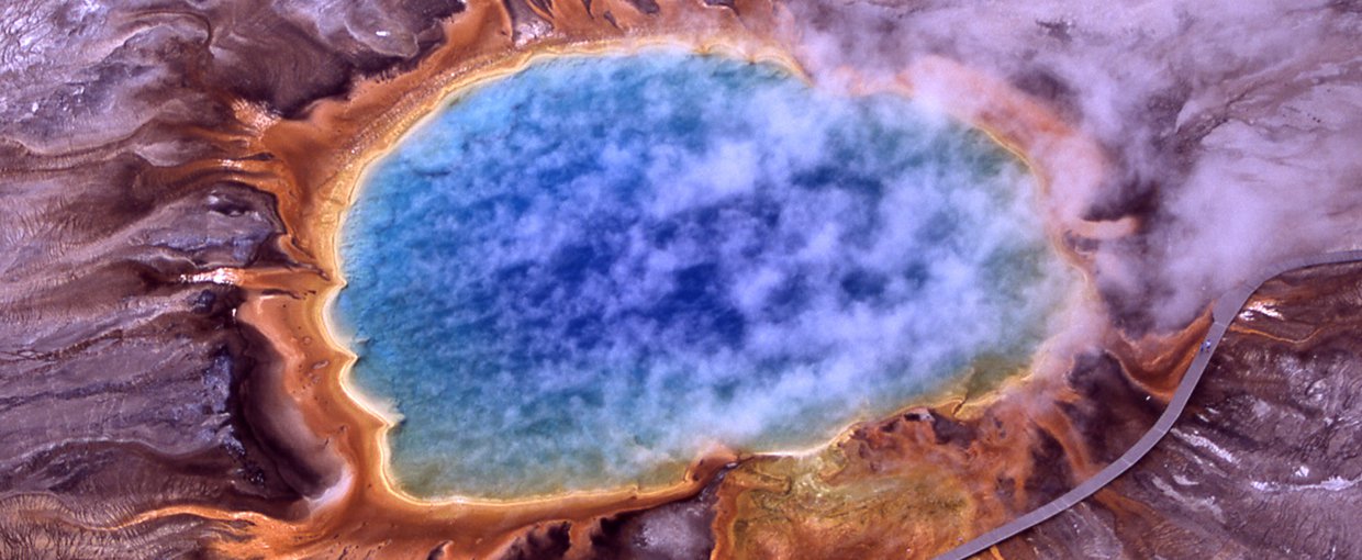 Image of a pruple blue spring surrounded by orange yellow and light purple land