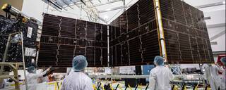 Technicians begin to retract one of the two solar arrays attached to NASAs Psyche spacecraft.