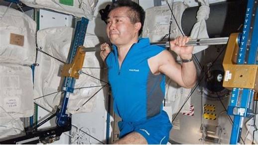 astronaut doing a barbell squat during training