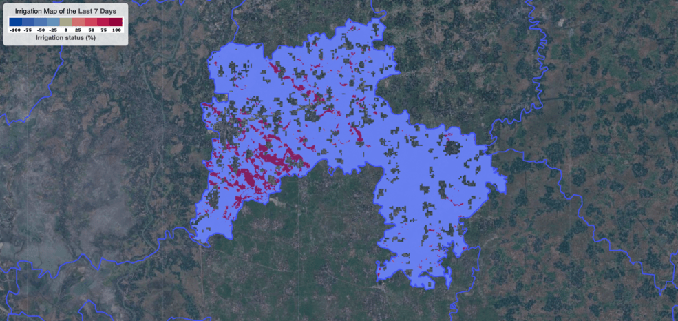 A muted satellite image of a region of farmlands of Bangladesh is overlayed with bright pixelated patches representing irrigation data. Most pixels are blue, or over-irrigated, with some red, or under-irrigated, areas to the left of the image.