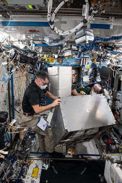 NASA astronauts Shane Kimbrough and Mark Vande Hei install the Four Bed CO2 Scrubber on the space station.