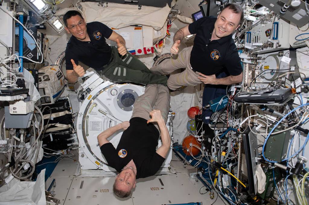 Three Expedition 69 crew members pose for a portrait