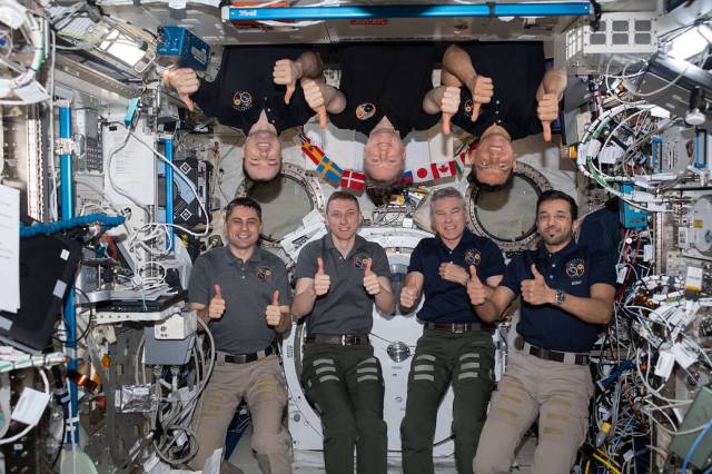 The seven-member Expedition 69 crew give a thumbs up