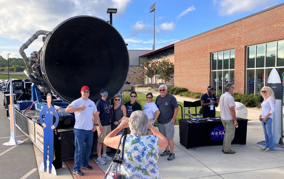 Fans pose for photos in front of an RS-25 engine exhibit during Space Night with the Rocket City Trash Pandas.