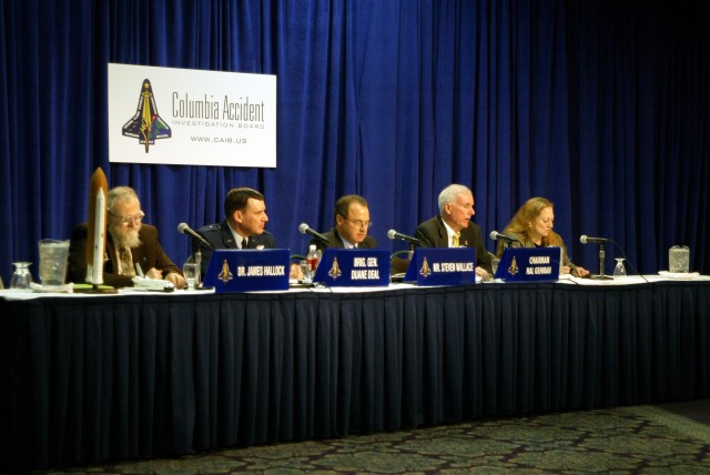 CAIB members sit at a table during a press briefing