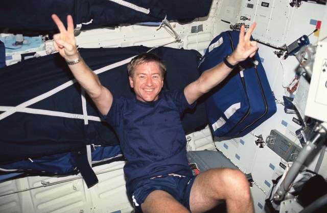 Astronaut Frank L. Culbertson Jr., STS-51 mission commander, appears to be enjoying a session on the ergometer, temporarily deployed on Discovery's middeck. There are sleep restraints attached to the wall behind him and a bag floating next to him.