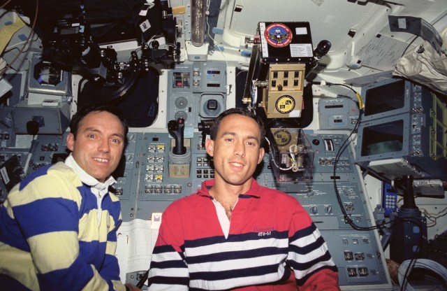Astronauts Carl E. Walz (left) and James H. Newman are pictured on Discovery's aft flight deck near two experiments. Positioned in the window above Walz's head is the Auroral Photography Experiment (APE-B), while the High Resolution Shuttle Glow Spectroscopy (HRSGS-A) experiment is deployed in the other window.