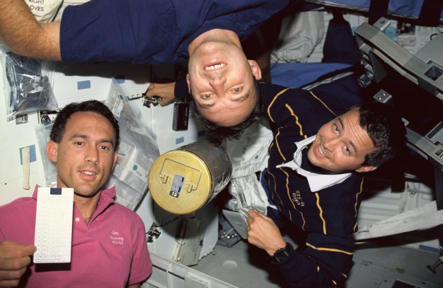 members of the astronaut class of 1990 change out a lithium hydroxide canister beneath Discovery's middeck during STS-51 mission.