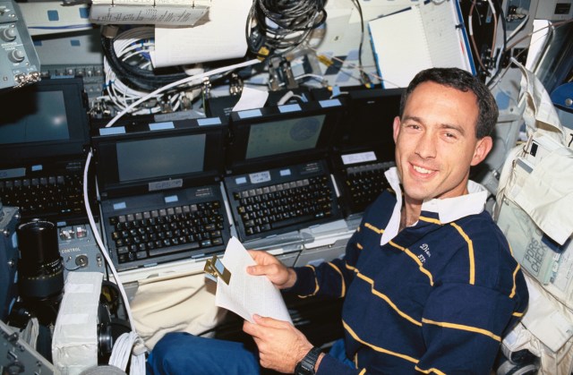 On Discovery's middeck, Astronaut James H. Newman, mission specialist, works with an array of computers, including one devoted to Global Positioning System (GPS) operations, a general portable onboard computer displaying a tracking map, a portable audio data modem and another payload and general support computer.