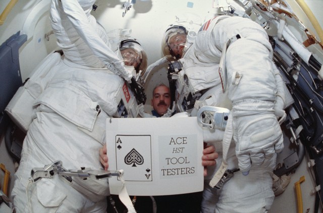 In Discovery's airlock, astronaut William F. Readdy, pilot, holds up a STS-51 slogan -- "Ace HST Tool Testers" -- for still and video cameras to record. Readdy is flanked by astronauts Carl E. Walz (left) and James H. Newman, who had just shared a lengthy period of extravehicular activity (EVA) in and around Discovery's cargo bay.