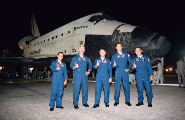 Standing in front of the Discovery, all five STS-51 crew members signal the successful completion of almost ten full days in space by giving the thumbs up sign.