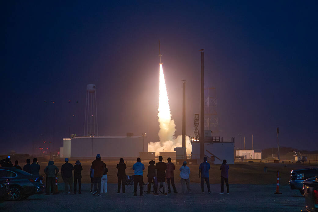 Students watch a sounding rocket launch at sunrise.