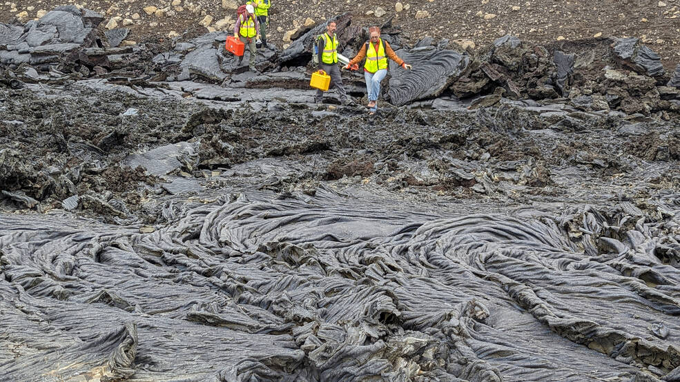 Members of the VERITAS science team descend a slope to new rock formed from a recent flow of lava during their Iceland field campaign in early August.