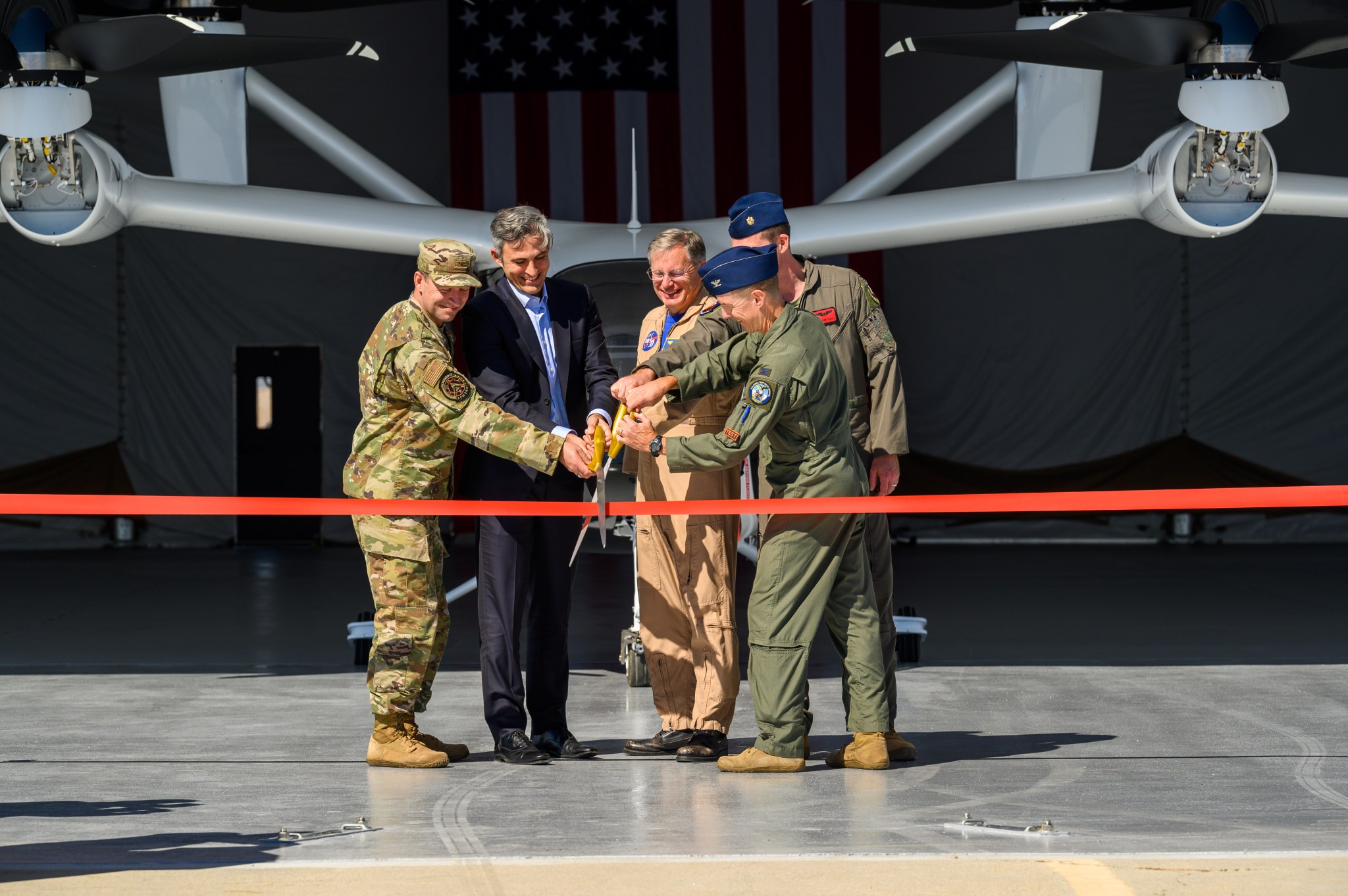 Members from the Air Force, Joby Aviation, and NASA cut a ribbon on Sept. 25 at Edwards Air Force Base in Edwards, California after opening a maintenance shelter for Joby's electric vertical takeoff and landing (eVTOL) aircraft.