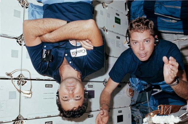 Mission Specialist (MS) David C. Leestma and Payload Specialist Marc Garneau floating on the middeck during the flight wearing headphones.
